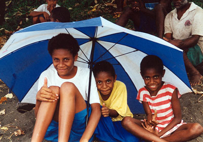 Priscilla, Enna and another girl wait huddled under umbrella